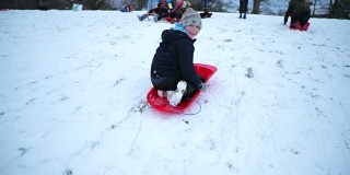 小男孩倒着玩雪橇