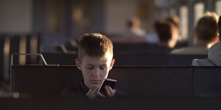 严肃的男孩坐火车玩手机