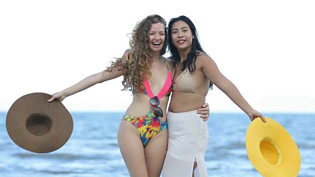 夏天，穿着比基尼的女人和朋友在海滩上散步。