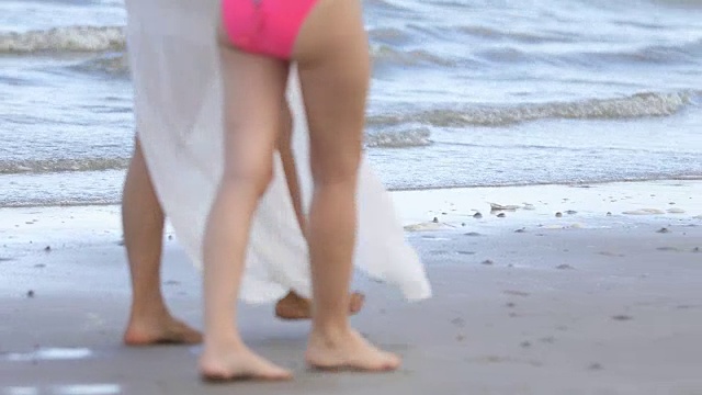 夏天，穿着比基尼的女人和朋友在海滩上散步。