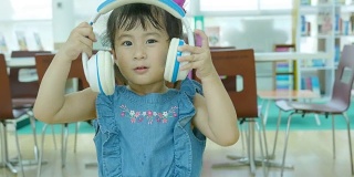 一个亚洲女孩戴着耳机唱歌听音乐