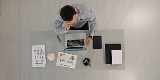 一个人坐在桌子前用笔记本电脑打字。俯视图