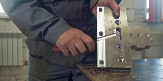 男性工作者用刮刀对金属本体进行研磨