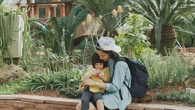 泰国女儿周末外出旅游，带着疲惫无聊的情绪和妈妈在公园里吃零食