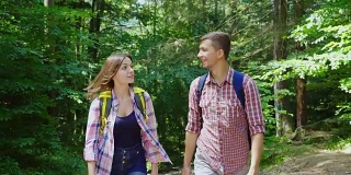 一个男人和一个女人走在树林里，在移动中交流，在行进中度过美好的时光