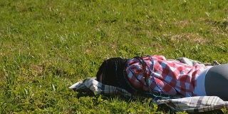 梳着蓝色非洲辫的陌生女人睡在公园的草坪上。