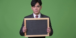 年轻英俊的亚洲商人展示黑板