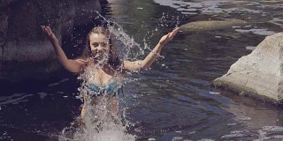 美丽的女孩穿着泳衣在溅水花的慢动作