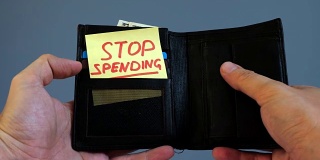 男人打开钱包，上面写着“停止消费”。浪费金钱的概念。