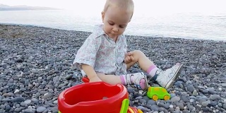 小男孩暑假在海滩上玩鹅卵石