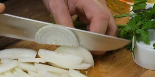 手用刀在厨房板上切洋葱。在家做饭