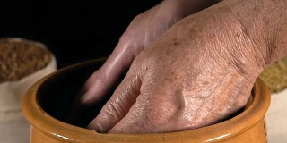 特写，慢镜头，老妇人的手把麦粒从陶罐里拿出来，倒在手里