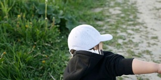 孩子穿着夹克，戴着兜帽，在田野里跑着