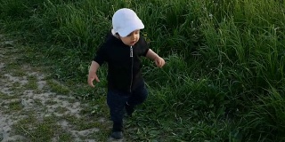 孩子穿着夹克，戴着兜帽，在田野里跑着