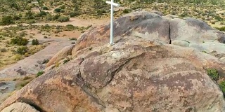 从空中俯瞰沙漠中央一座山的白色十字架