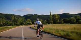 年轻男子运动员在乡间公路上骑自行车