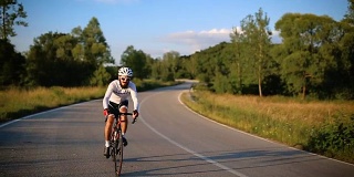 年轻男子运动员在乡间公路上骑自行车