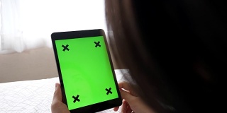 一个女人的手握绿色屏幕平板电脑的特写