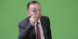 成熟的日本商人使用放大镜
