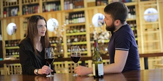 一个女孩和一个男孩在餐厅交流和喝红酒，一对年轻的夫妇在餐厅或咖啡馆的桌子上喝红酒