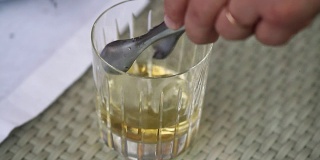 服务员把冰块放在一个有威士忌的杯子里，一杯威士忌放在桌子上，一杯威士忌放冰块，一杯威士忌加冰在桌子上