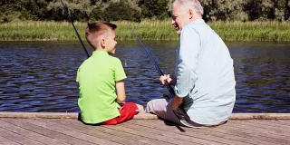 快乐的爷爷和孙子在河边钓鱼