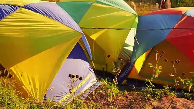 全视频高清旅行和露营概念，从彩色帐篷设置后，在山上移动的风与阳光和森林背景