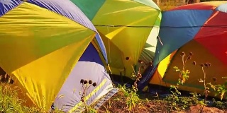 全视频高清旅行和露营概念，从彩色帐篷设置后，在山上移动的风与阳光和森林背景