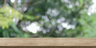 空木桌面与模糊的绿树在公园散景灯光背景，背景模板的产品或设计展示，食品站模拟