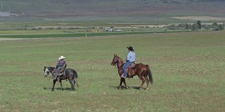 空中拍摄的牛仔父亲和儿子在马背上