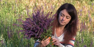 特写，美丽的女人收集矢车菊花束，坐在野外的花在早晨在树林里
