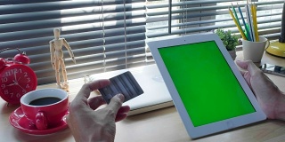 潮人手握信用卡，用绿色空白屏幕的平板电脑在网上购物。网上购物的概念。电影模拟绮年华。