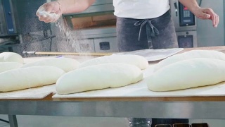 烘焙师在烘焙前将面粉洒在生面包上视频素材模板下载