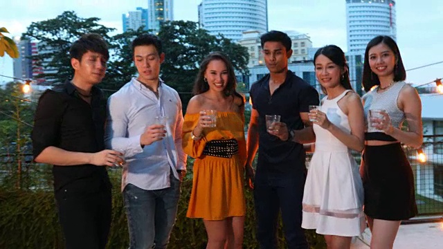 一群亚洲年轻人在屋顶上聚会和敬酒的视频