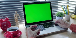 商人手里拿着信用卡，用现代的笔记本电脑和空白绿色屏幕进行网上购物。网上购物的概念。绮年华电影模拟