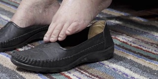 老妇人肿胀的脚在家里穿鞋
