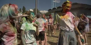 夏日的胡里节上，三位年轻的多民族女友在白天带着五颜六色的粉蹦蹦跳跳，友情概念，色彩概念
