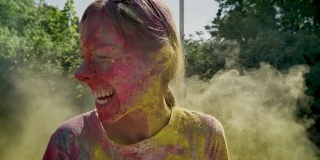 年轻快乐的女孩在夏天的白天里被泼上黄色的粉，欢笑着，色彩概念