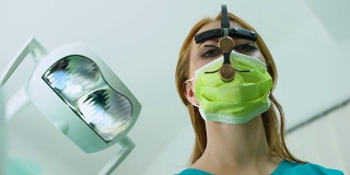 年轻女牙医戴着放大镜检查口腔，病人POV