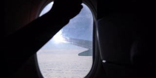 一只手在飞机舷窗上打开和关闭一扇窗户