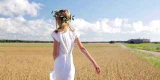 微笑的年轻女子在白色的裙子在谷物地里