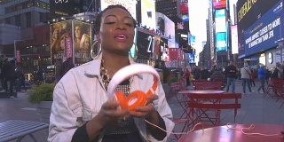 年轻的非洲裔美国妇女在纽约时代广场听着老式耳机，然后和你分享