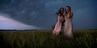 两个年轻迷人的女孩穿着裙子在夏天的雨天享受风，自由的概念，调情的概念