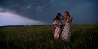 两个年轻迷人的女孩穿着衣服在雨中享受风与闪电的夏天，自由的概念，调情的概念