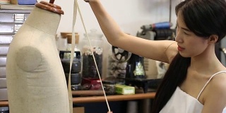亚洲女性时装或设计师与裁减人体模特工作的一卷织物