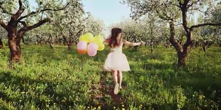 快乐的女孩与气球在盛开的花园中奔跑