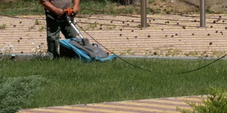 工作的园丁用电动割草机割草