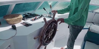 这位不知名的主人通过一个复古的方向盘和控制杆来管理游艇。经营或生活管理、度假或旅游的概念