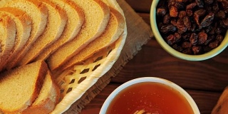 蜂蜜壶和长柄勺在乡村的桌子上，面包，葡萄干和蜂蜜梳子，俯视图