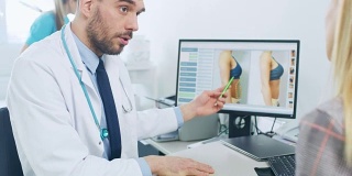 整形/整容外科医生向女性患者展示抽脂术的可能结果，他指出电脑屏幕上显示胃部脂肪组织减少。